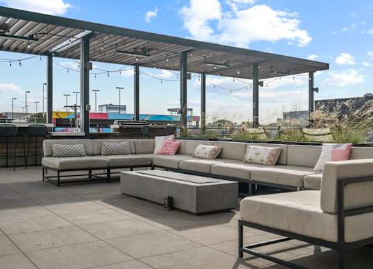 A patio with a white couch and a grey couch with a table in between.