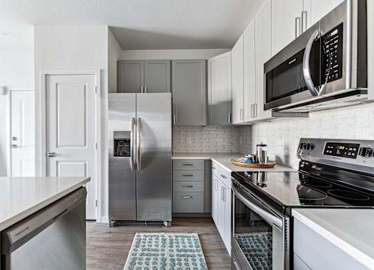 A kitchen with a refrigerator, microwave, and oven.
