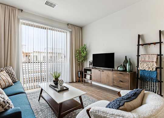 A living room with a blue couch, a white chair, and a wooden coffee table.