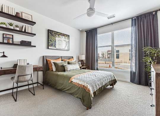 A bedroom with a bed, desk, and chair.