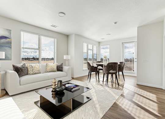 A modern living room with a white sofa, a coffee table, and a dining table with chairs.