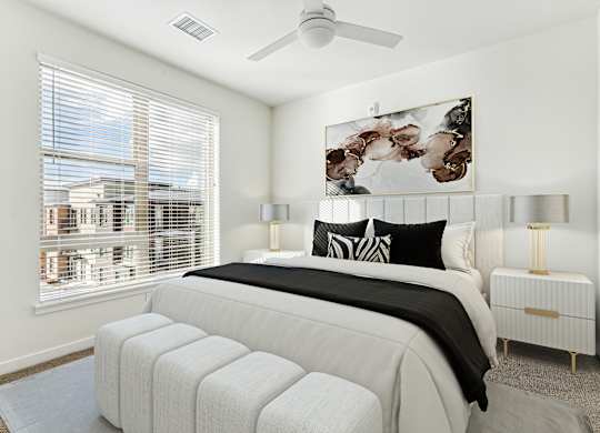A bedroom with a large bed, a ceiling fan, and a window with blinds.
