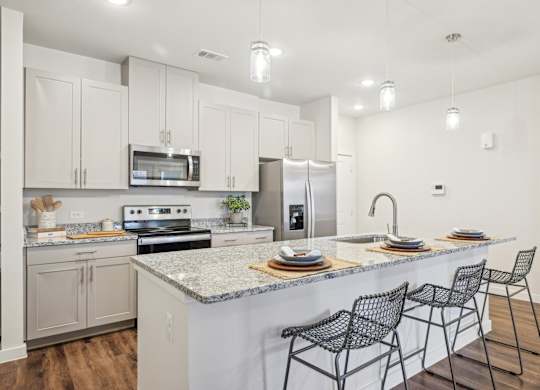 A kitchen with a white counter top and black chairs.