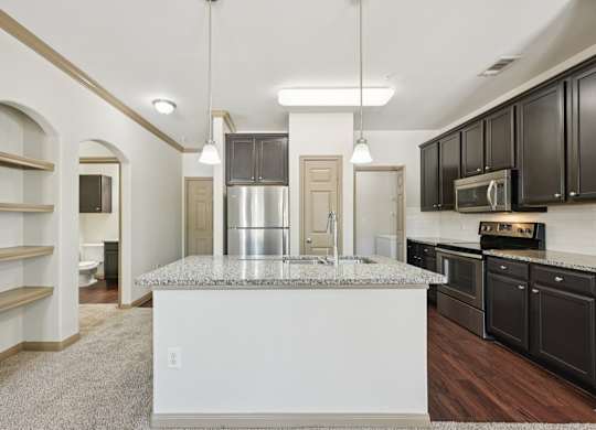 A kitchen with a granite countertop and black cabinets.