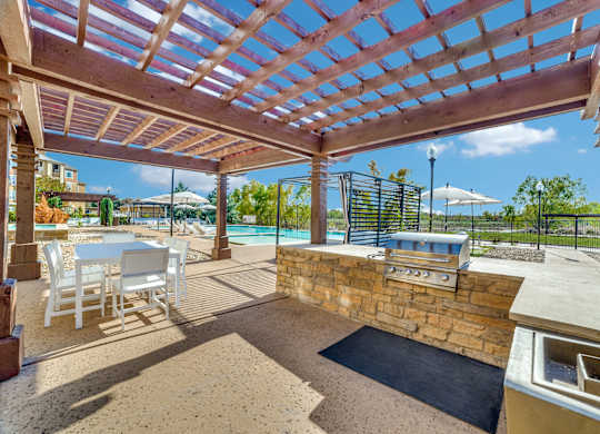 a patio with a barbecue grill and a table and chairs