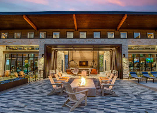 A modern outdoor seating area with a fireplace and chairs.