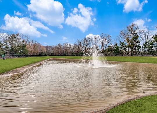 A fountain in the middle of a pond in a park.