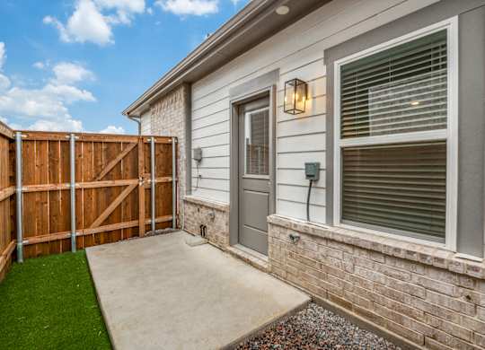 A house with a grey door and a brown fence.