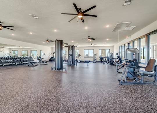 A spacious gym with a variety of equipment and a ceiling fan.