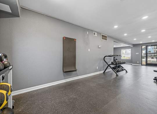 A gym with a grey floor and a row of exercise equipment.