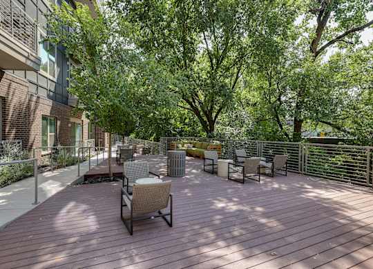 A wooden deck with chairs and trees in the background.