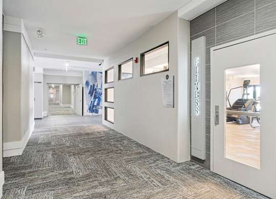 A hallway with a carpeted floor and a white door on the right.
