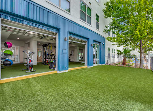 a home gym with a green lawn and a building with blue doors