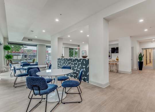 A modern dining room with a white table and blue chairs.