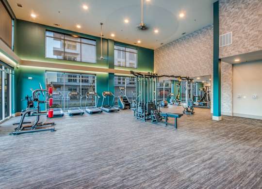 A gym with a variety of equipment including treadmills, weights, and exercise machines.