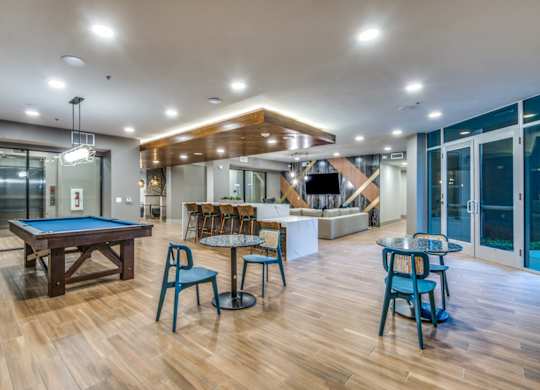 A room with a pool table and chairs.