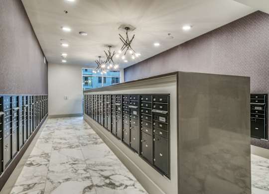 A long hallway with a marble floor and a wall of elevators.