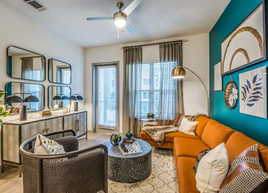 A living room with a brown chair, a round table, and a mirror on the wall.