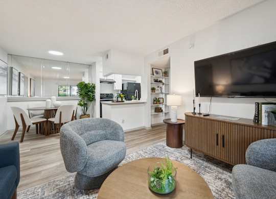 A living room with a grey armchair, a wooden coffee table, and a flat screen TV.