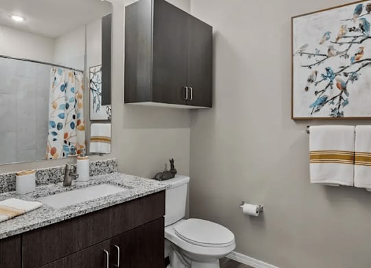 A bathroom with a toilet, sink, and a painting on the wall.