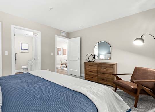 a bedroom with a bed and a dresser and a bathroom