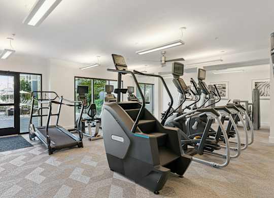 A gym with treadmills, elliptical machines, and other exercise equipment.