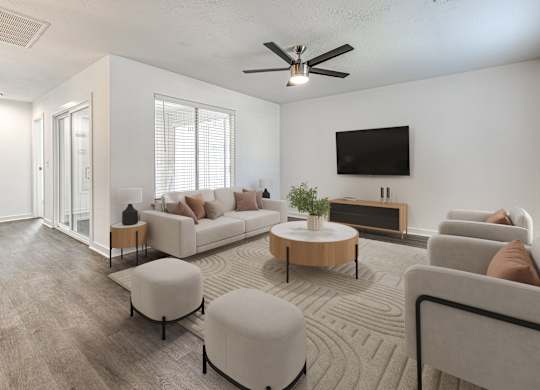 A living room with a white couch, a wooden coffee table, and a flat-screen TV mounted on the wall.