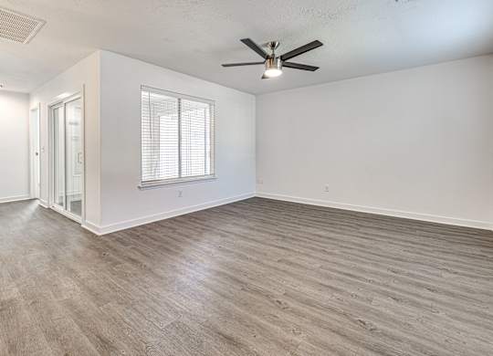 A room with a ceiling fan and a window with blinds.