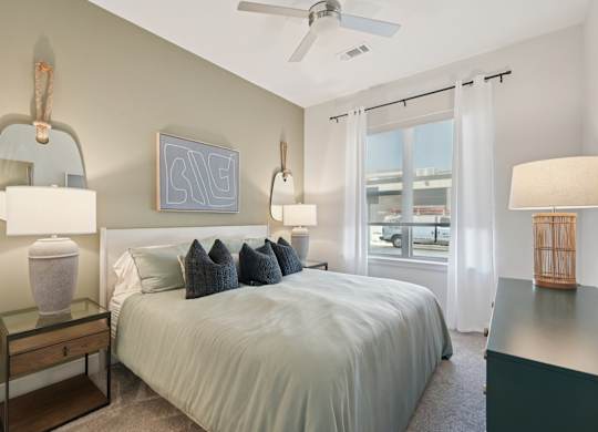 A bedroom with a bed, nightstand, and a window with curtains.