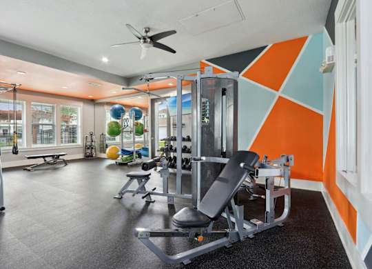 A gym with orange and blue walls and a variety of equipment.