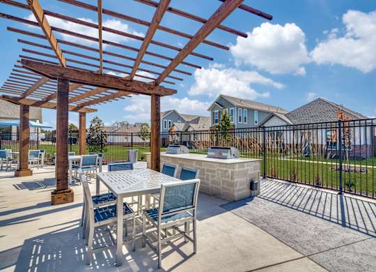 A patio with a table and chairs under a wooden pergola.