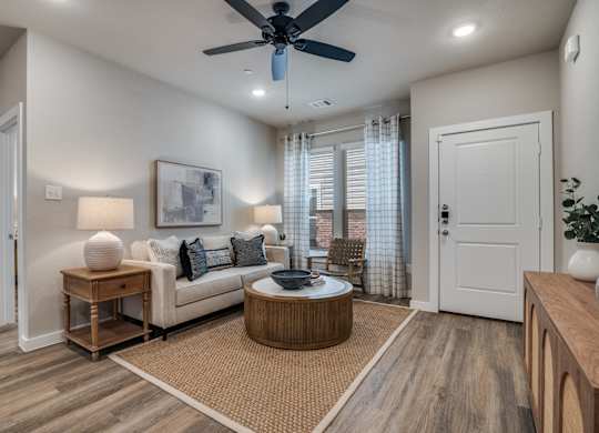 A living room with a white couch, a round coffee table, and a ceiling fan.