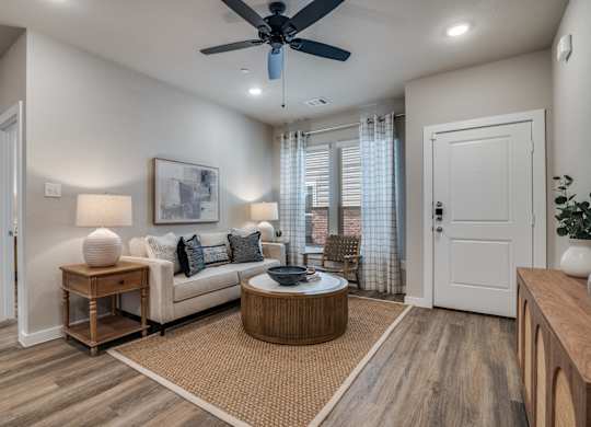 A living room with a white couch, a round coffee table, and a ceiling fan.