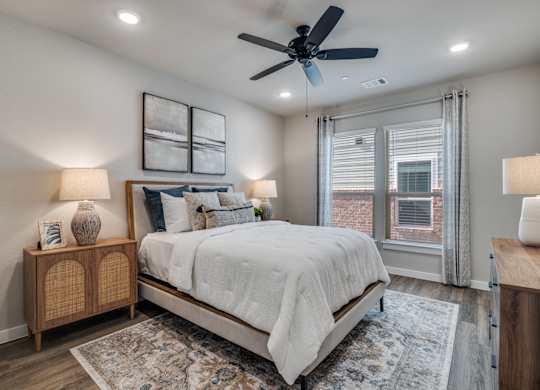 A bedroom with a bed, a ceiling fan, and a rug.