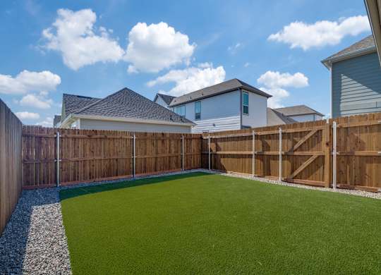 A backyard with a green lawn and a wooden fence.