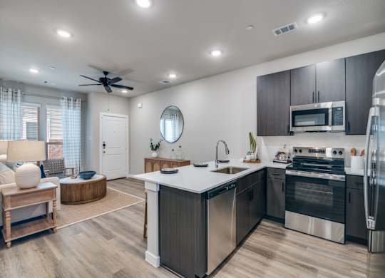 A modern kitchen with stainless steel appliances and wooden flooring.