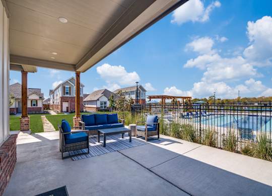 A patio with a couch and chairs overlooking a pool.