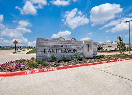 A sign for Cottages at Lake Lavon is displayed in front of a building.