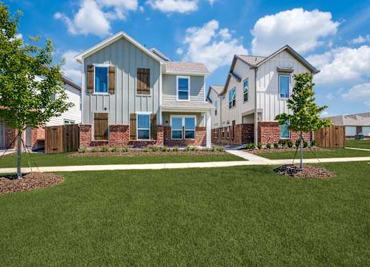 A row of houses with a green lawn in front.