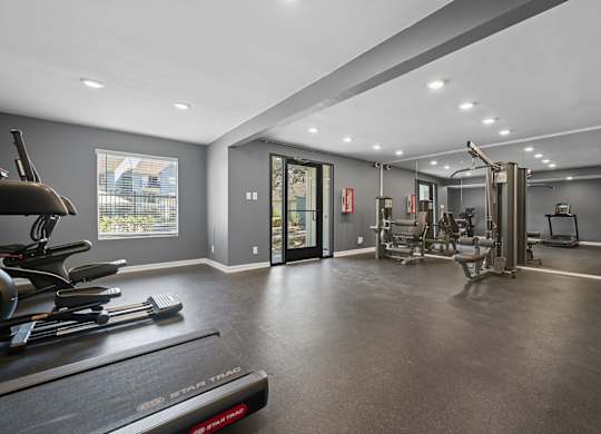 A spacious home gym with a treadmill, elliptical machines, and other exercise equipment.