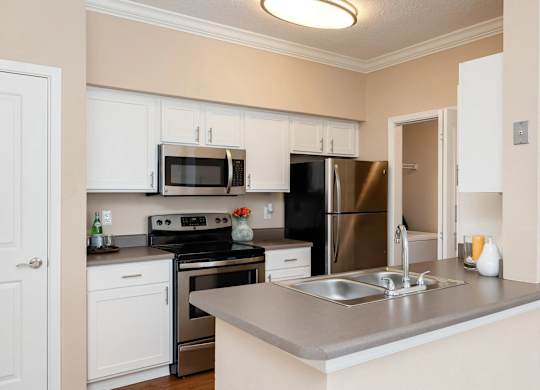 A kitchen with a stove, oven, refrigerator, and microwave.