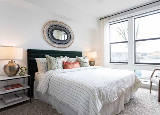 A bedroom with a large bed and a mirror on the wall.