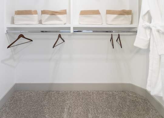 A white closet with two shelves and two hangers.