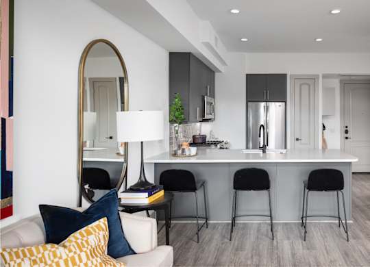 A modern kitchen with a white countertop and black bar stools.