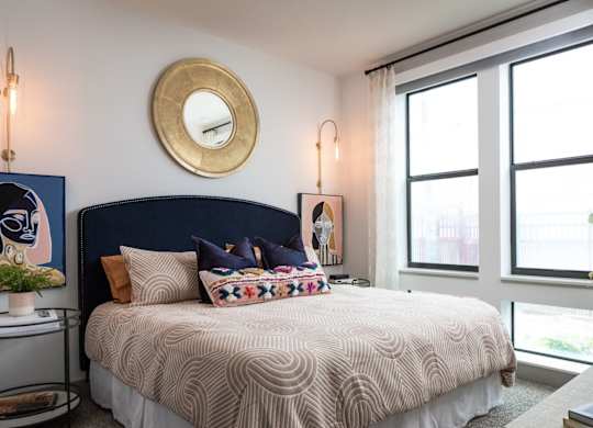 A bedroom with a large bed and a round mirror on the wall.