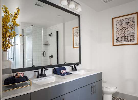 A bathroom with a white sink and a large mirror.