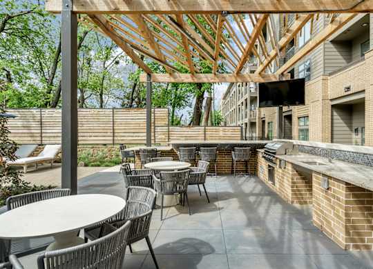 A patio with tables and chairs under a wooden roof.