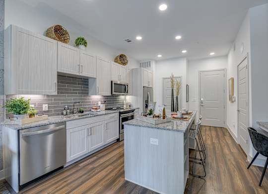 A modern kitchen with white cabinets and a wooden floor.