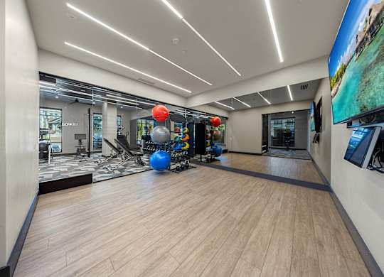 A spacious room with wooden flooring and a large screen on the wall.