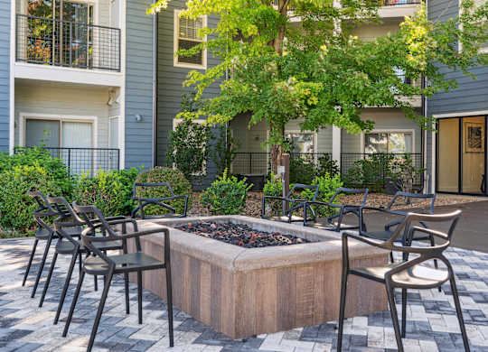 A patio with chairs and a fire pit in front of a building.